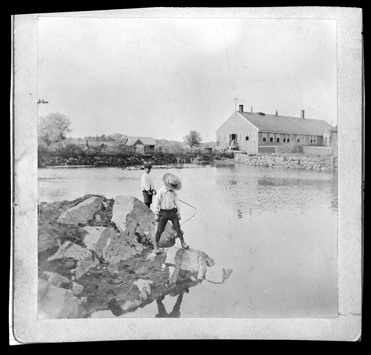 Two boys fishing in the millpond of C. Drew & Co., no date